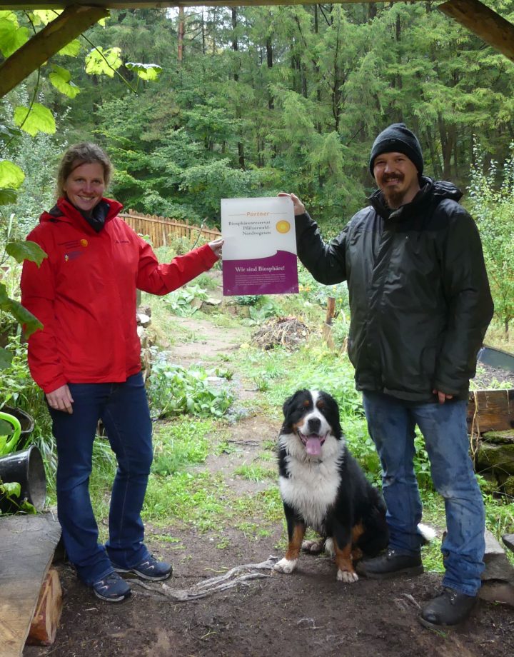 Die Direktorin des Biosphärenreservats Pfälzerwald, Dr. Friedricke Weber, und der pädagogische Leiter der Waldritter Südwest e.V., Dieter Simon, stehen am Eingang zum Wildkräutergarten der Waldritter Südwest, der gemeinsam mit vielen Kindern und Jugendlichen angelegt wurde.