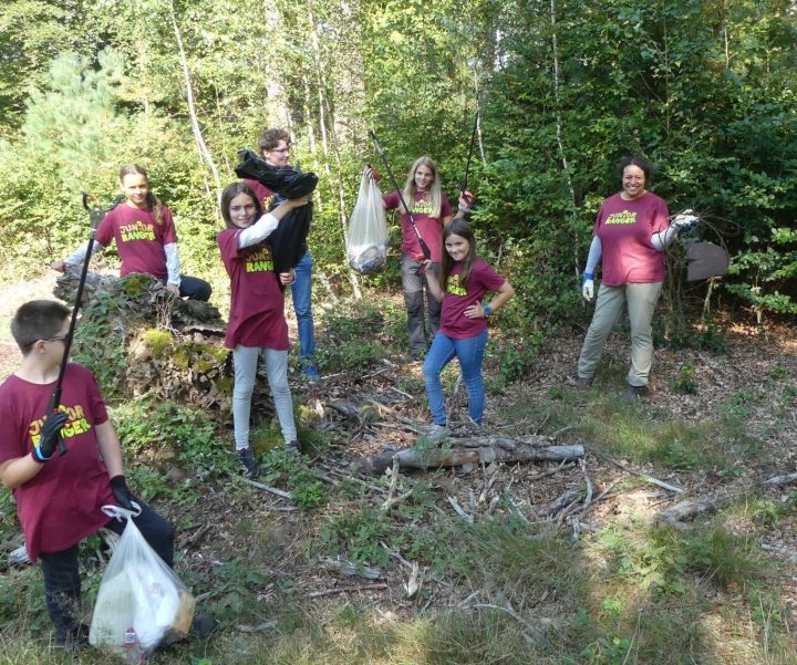 Das Bild zeigt eine Gruppe Junio Ranger:innen, die stolz ihre vollen Müllsäcke zeigen