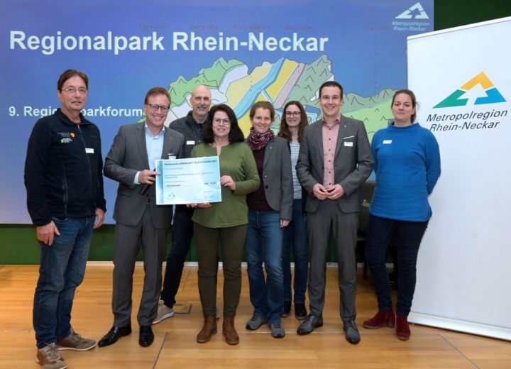 Das Bild zeigt 8 Personen vor einer Wand it der Aufschrift "Regionalpark Rhein-Neckar"